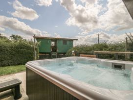 An outdoor hot tub with bubbling water in a garden area near a small green wooden cabin at Wayside Cottage in Pocklington
