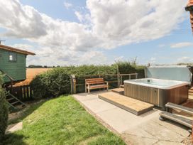 A garden area with a hot tub bench and wooden steps near a green wooden hut at Wayside Cottage in Pocklington