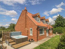 A brick house with a red tiled roof and a hot tub in the garden at Wayside Cottage in Pocklington