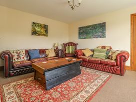 A living room with two red leather sofas an armchair a wooden coffee table and paintings on the wall at Wayside Cottage in Pocklington