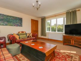 A living room with red leather sofas a wooden coffee table a television on a wooden cabinet and green curtains at Wayside Cottage in Pocklington