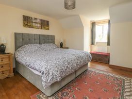 A bedroom with a large bed two wooden bedside tables and a patterned rug at Wayside Cottage in Pocklington