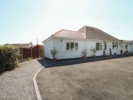 A white single-story house with potted plants along the front wall and a paved driveway at Beachway in Talacre near Prestatyn