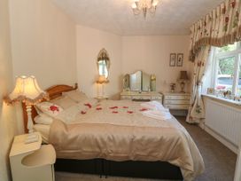 A bedroom with a bed a dressing table lamps and a window at Beachway in Talacre near Prestatyn