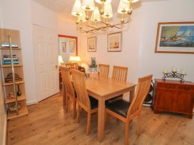 A dining room with a wooden table and six chairs a bookshelf a sideboard with candles and framed pictures on the walls at Beachway Talacre near Prestatyn