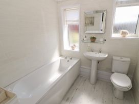 A bathroom with a bathtub sink toilet and two windows at Beachway in Talacre near Prestatyn