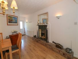 A dining area with wooden table and chairs a fireplace with a mirror above and a hallway with a door at Beachway in Talacre near Prestatyn