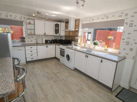A kitchen with white cabinets appliances and two metal bar stools at Beachway in Talacre near Prestatyn