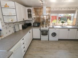 A kitchen with white cabinets countertop appliances and a window overlooking a garden at Beachway Talacre near Prestatyn