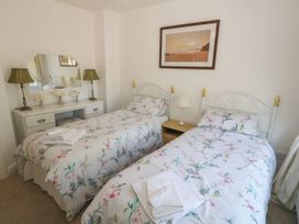 A bedroom with two single beds a dressing table with two lamps and a mirror a framed picture on the wall at Beachway Talacre near Prestatyn