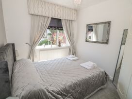 A bedroom with a bed covered in gray bedding two windows with curtains and a radiator under the windows at Beachway Talacre near Prestatyn