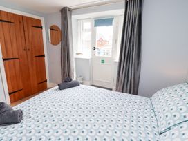 A bedroom with a bed and wooden wardrobe at Hasting Dairy in North Sunderland near Seahouses