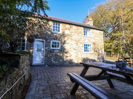 An outdoor area with a stone house and patio furniture at Woodland Cottage in Garth