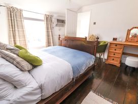 A bedroom with a bed and a chair at Woodland Cottage in Garth