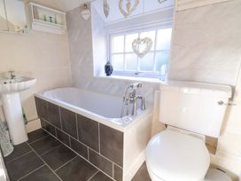 A bathroom with a bathtub, toilet, and sink at Woodland Cottage in Garth