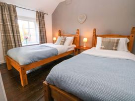A bedroom with two beds and a window at Woodland Cottage in Garth