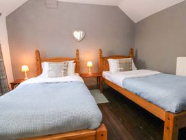 A bedroom with two beds and a nightstand at Woodland Cottage in Garth