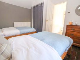 A bedroom with two beds and a dresser at Woodland Cottage in Garth