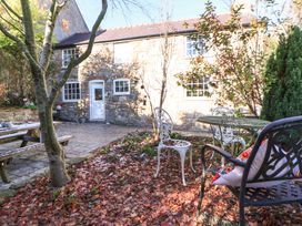 A stone house with a table and chairs in the garden at Woodland Cottage in Garth