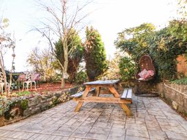 A garden with a picnic table and a hanging chair at Woodland Cottage in Garth