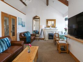 A living room with brown leather sofas a wooden coffee table a tall mirror a fireplace a dining table with chairs and a wall mounted television at Bay View Apartment in Porthmadog