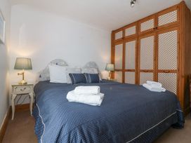 A bedroom with a large bed with blue polka dot bedding two bedside tables with lamps and a wooden wardrobe at Bay View Apartment in Porthmadog