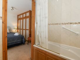 A bathroom with a bathtub and shower curtain next to a bedroom with a bed lamp and wardrobe at Bay View Apartment in Porthmadog