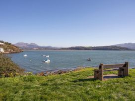 A view of the water with boats and a bench at Bay View Apartment in Porthmadog