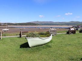 A view of a river with boats and people sitting on benches at Bay View Apartment in Porthmadog