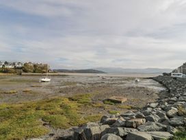 A view of boats on the water with rocks and grass at Bay View Apartment in Porthmadog