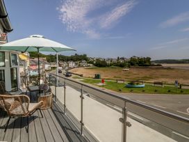 A balcony with chairs and an umbrella overlooking a view at Bay View Apartment in Porthmadog