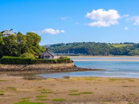 A house near water with trees and a sandy area at Bay View Apartment in Porthmadog