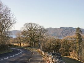 A road with trees and mountains near water at Heights View