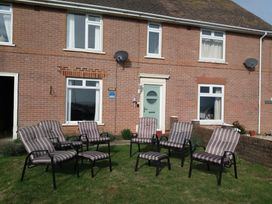A garden with chairs in front of a brick house at The Lookout -The House With A View Weymouth
