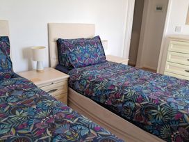 A bedroom with two beds and a bedside lamp at The Lookout - The House With A View Weymouth