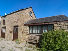 An exterior view of a stone building with a bench at Kernyk in Penzance