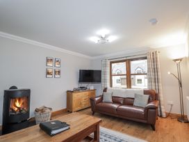 A living room with a fireplace and a sofa at Burnside House in Aviemore