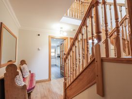 A hallway with a staircase and bench at Burnside House Aviemore