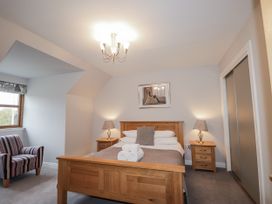 A bedroom with a bed and a chair at Burnside House in Aviemore