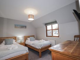 A bedroom with two single beds and a wooden table at Burnside House in Aviemore