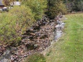 A stream with rocks and greenery at Burnside House Aviemore