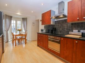 A kitchen with cabinets and a dining table at Bwthyn Llechen in Porthmadog