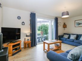 A living room with a television, sofa, and coffee table at Bwthyn y Mor in Borth-y-Gest near Porthmadog