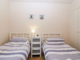 A bedroom with twin beds and a nightstand at Bwthyn y Mor Borth-y-Gest near Porthmadog