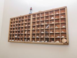 A wooden display case filled with shells and a lighthouse figurine at Bwthyn y Mor in Borth-y-Gest near Porthmadog