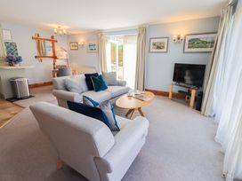 A living room with a sofa, armchair, and television at Lakeside Cottage in Ecclerigg near Ambleside