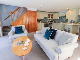 A living room with a staircase and kitchen cabinets at Lakeside Cottage in Ecclerigg near Ambleside