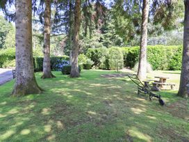 A garden with trees, a stone table and a garden bench at Lakeside Cottage in Ecclerigg near Ambleside
