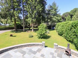 A garden with trees and a stone patio at Waterhead Cottage, Ecclerigg, near Troutbeck Bridge