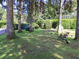 A garden with trees, a bench, and a table at Waterhead Cottage, Ecclerigg, near Troutbeck Bridge
